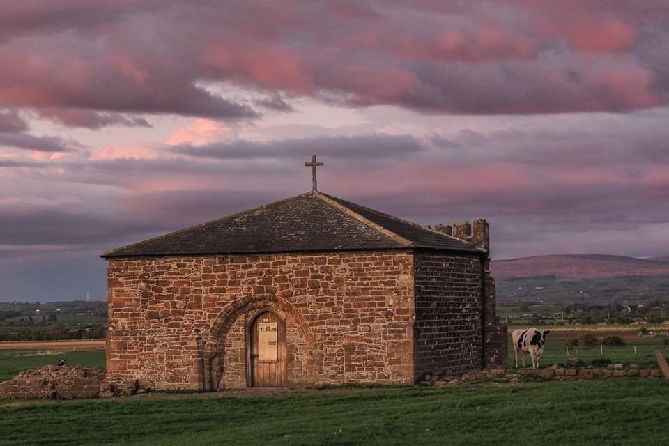 The stone chapterhouse at Cockersands Abbey beneath a pink evening sky